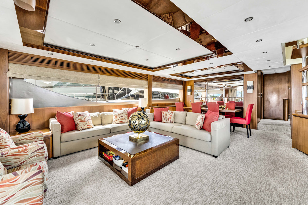 Main saloon aboard PRAYING FOR OVERTIME: cream sofas, coral cushions and walnut joinery, dining table beyond