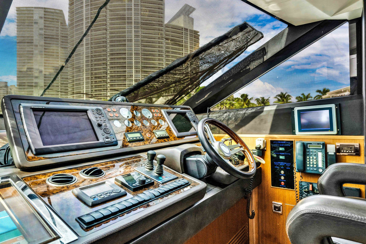 Interior helm station of PRAYING FOR OVERTIME, wheel, throttles and screens, Miami high-rises through the glass