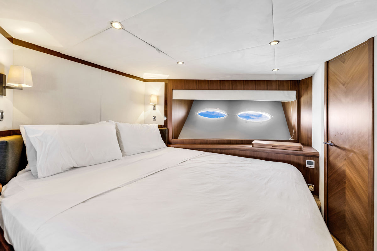 Forward VIP cabin aboard PRAYING FOR OVERTIME, crisp white bedding, twin portholes and walnut panelling
