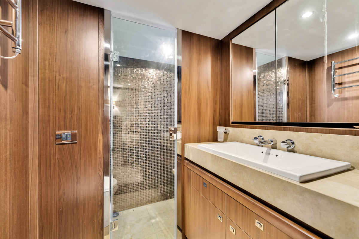 Guest head on PRAYING FOR OVERTIME, walnut panelling, stone basin and a glass-enclosed mosaic shower