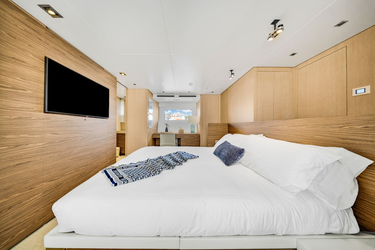 Full-beam master stateroom on ASTONISH, king berth flanked by hull windows in pale oak