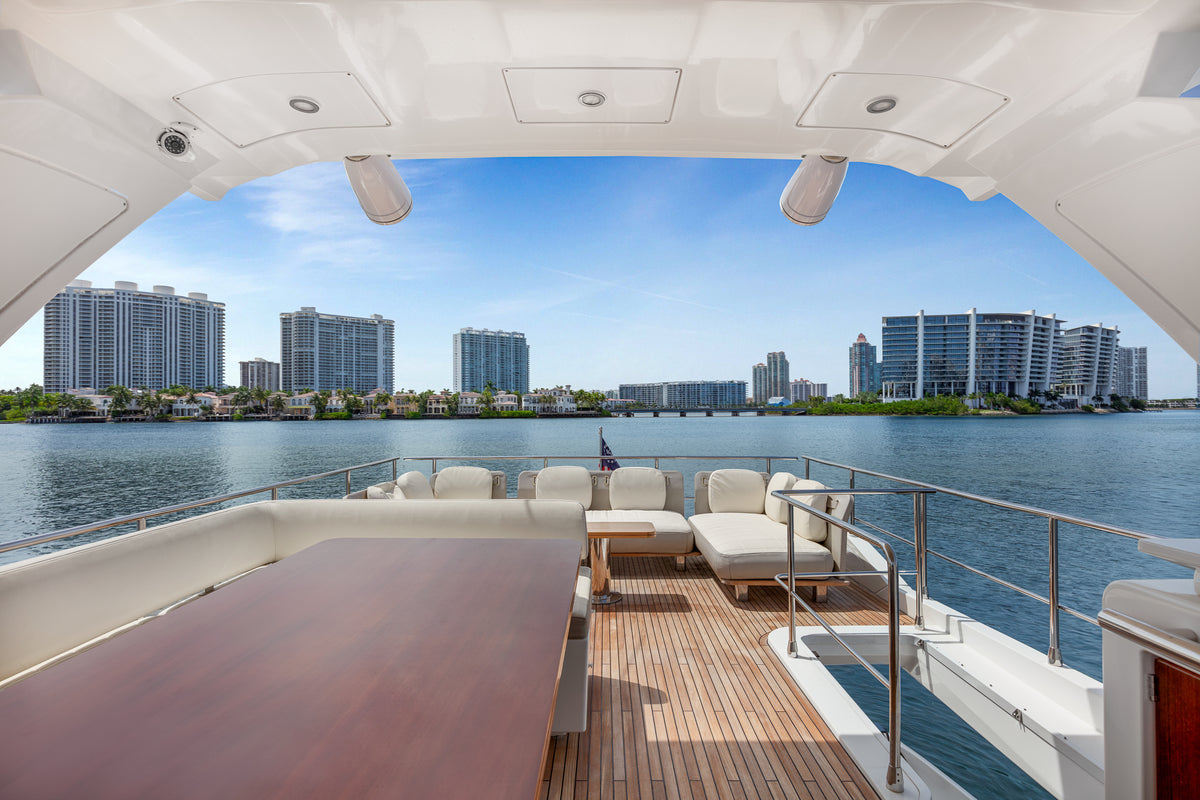 Teak flybridge deck on Le Grand Bleu, with a dining table and lounge seating over the water