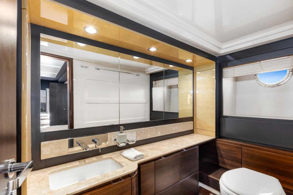 En suite bathroom on Le Grand Bleu, with a marble vanity, wide mirror and porthole