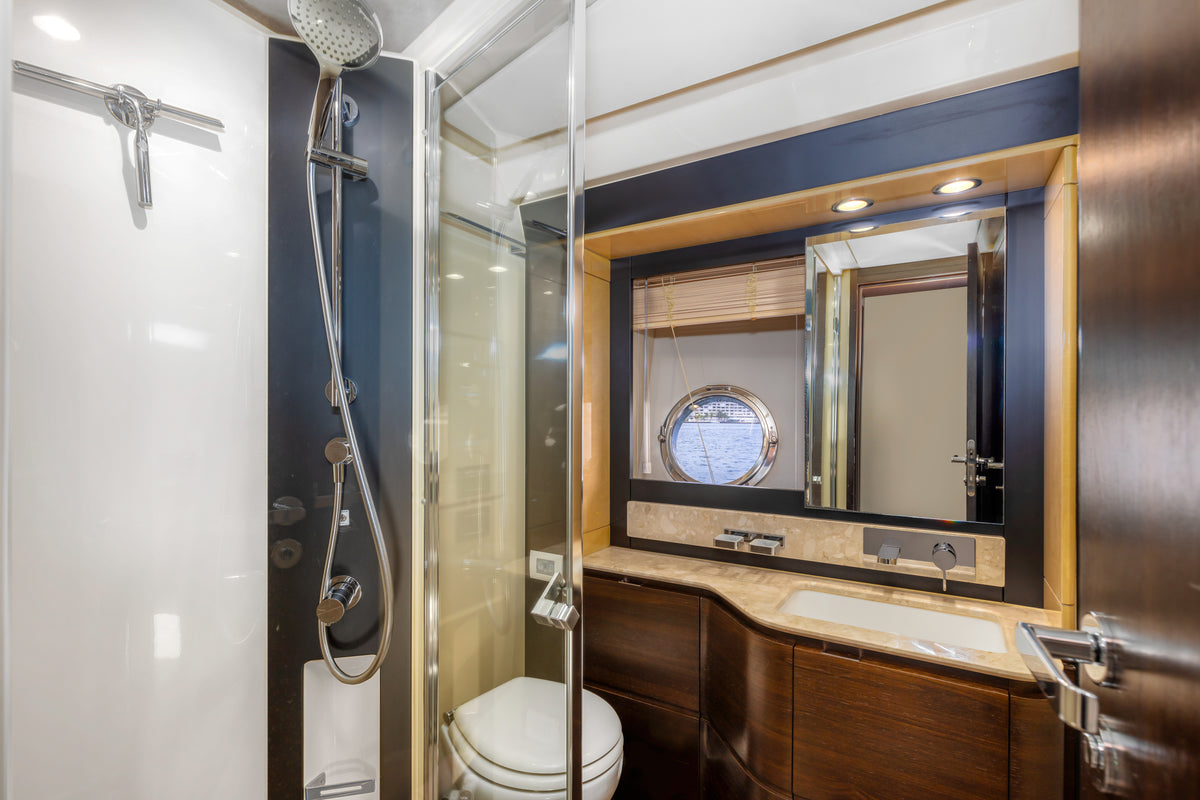 Guest head on Le Grand Bleu, with a glass shower stall, vanity and porthole