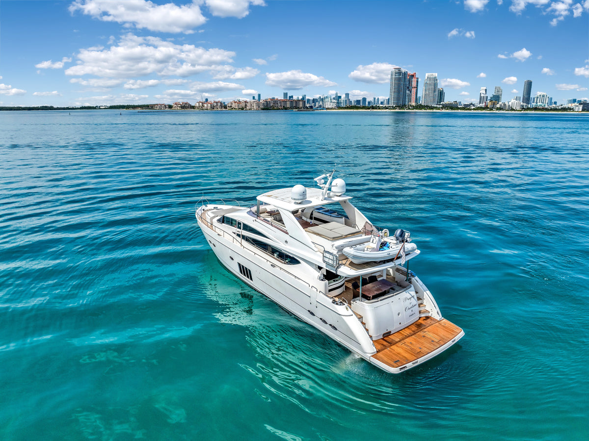 Stern quarter of PRAYING FOR OVERTIME, an 88ft Princess, at anchor in turquoise water off the Miami skyline