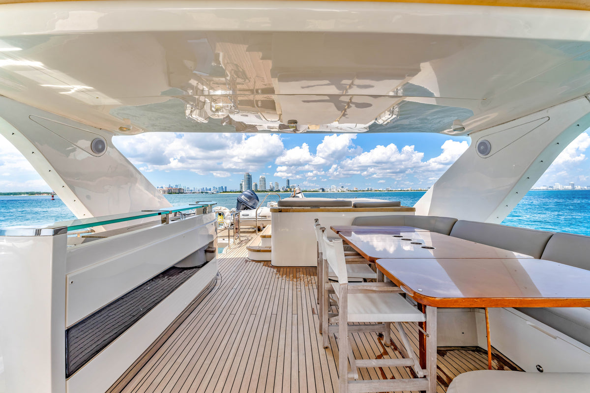 Shaded flybridge seating and high table aboard PRAYING FOR OVERTIME, with the skyline off the stern