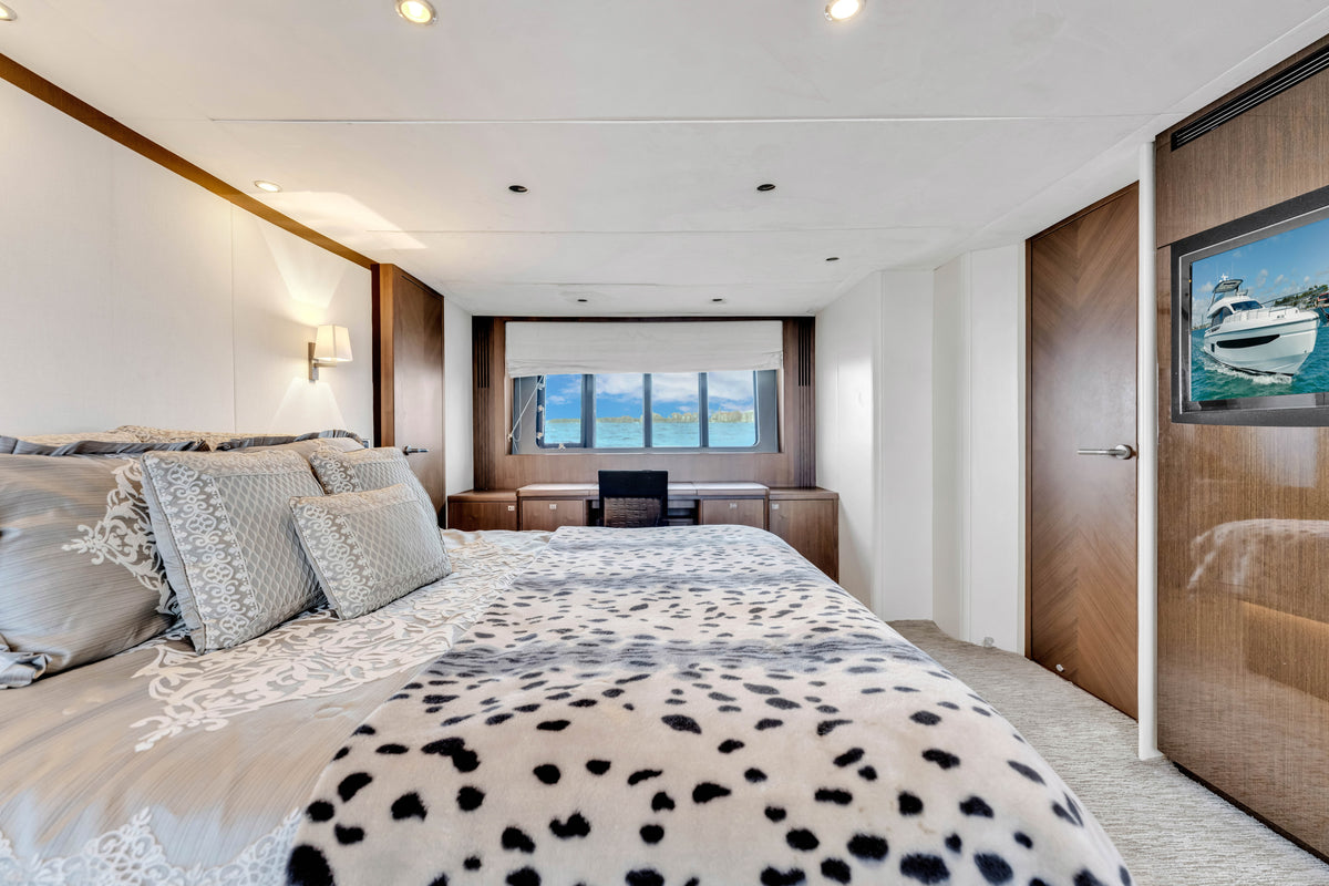 Full-beam master stateroom on PRAYING FOR OVERTIME, king bed, grey linens, desk and hull window