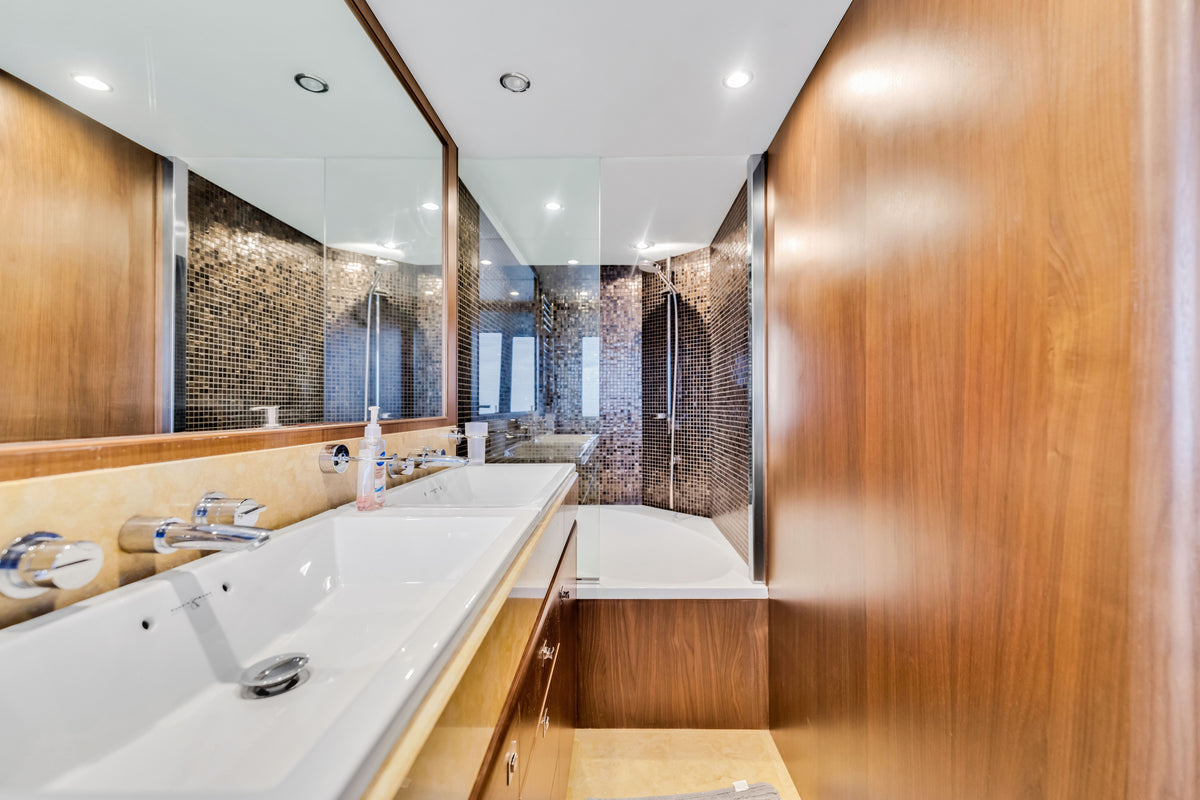 Master bathroom aboard PRAYING FOR OVERTIME with a long stone basin, mirrored wall and mosaic-tiled shower