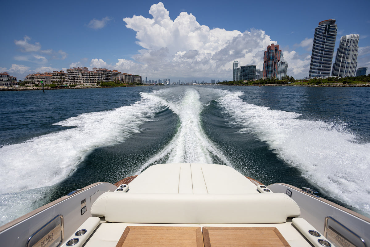 Aft sun pad on the Solaris Power with a white wake and Miami Beach towers behind