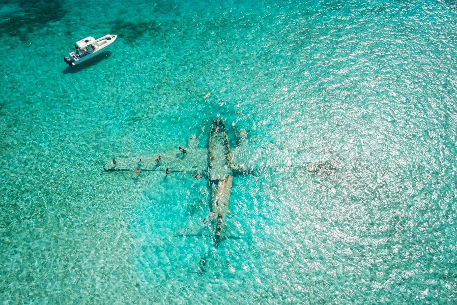 Aerial view of snorkelers exploring the submerged plane wreck at Norman's Cay in the Exumas, Bahamas.